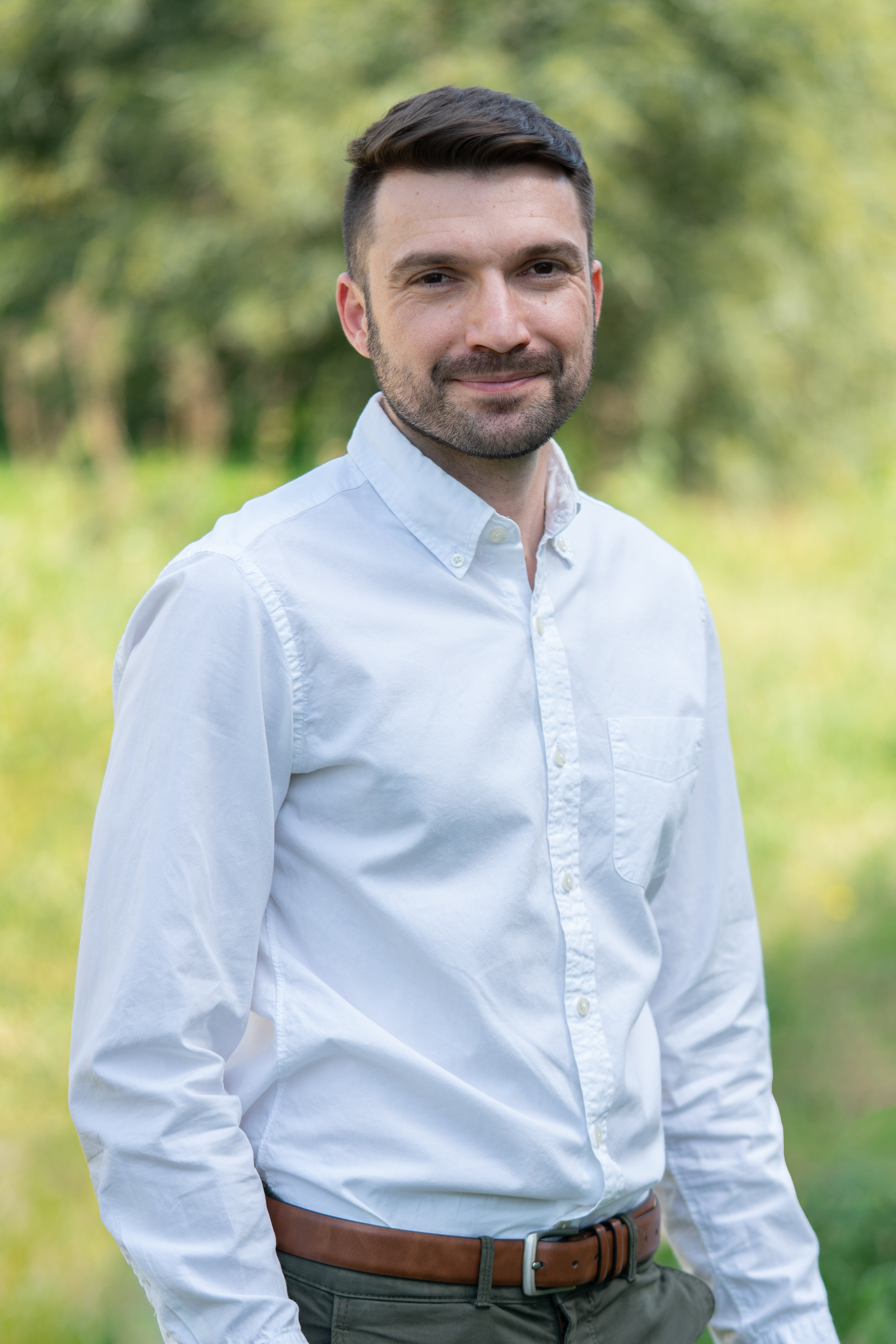 מצולם לובש חולצה לבנה על רקע שדה ירוק