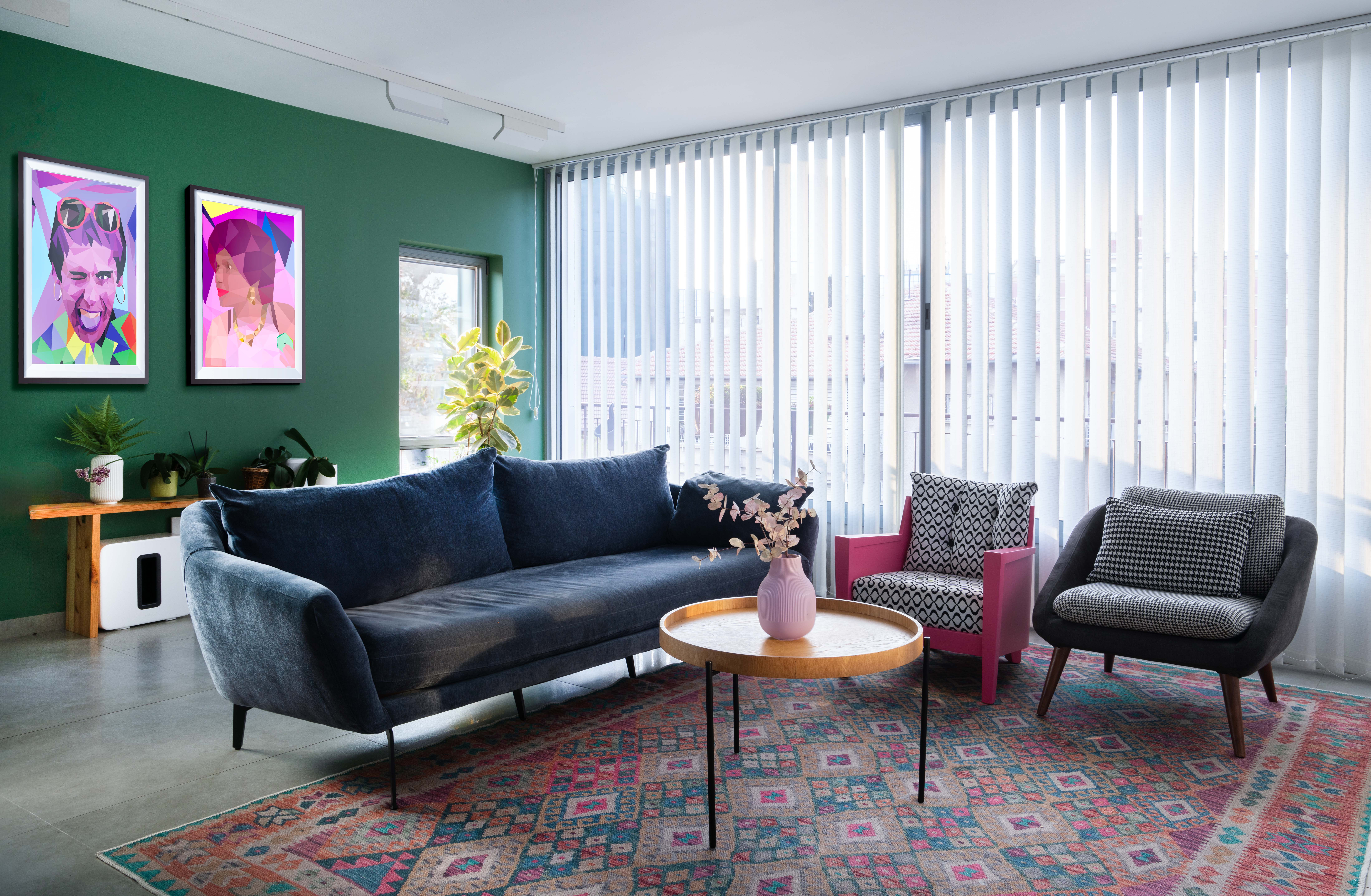 תמונה של סלון צבעוני. קיר ירוק ספה כחולה שטיח צבעוני, כורסה ורודדה וכורסה אפורה