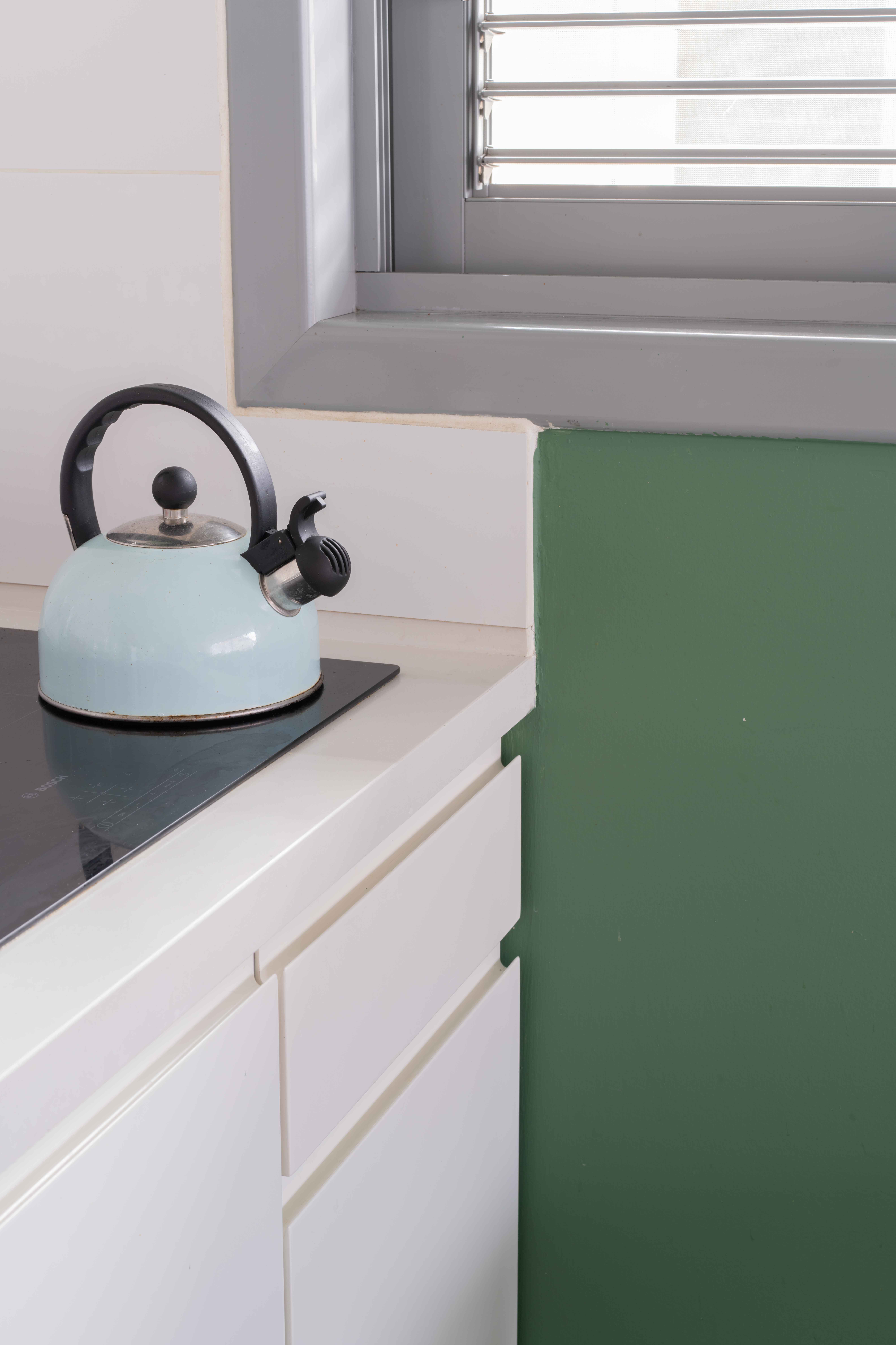 קלוז אפ מדטבח קיר ירק קומקום בצבע טורקיז וכיריים אינדוקציה