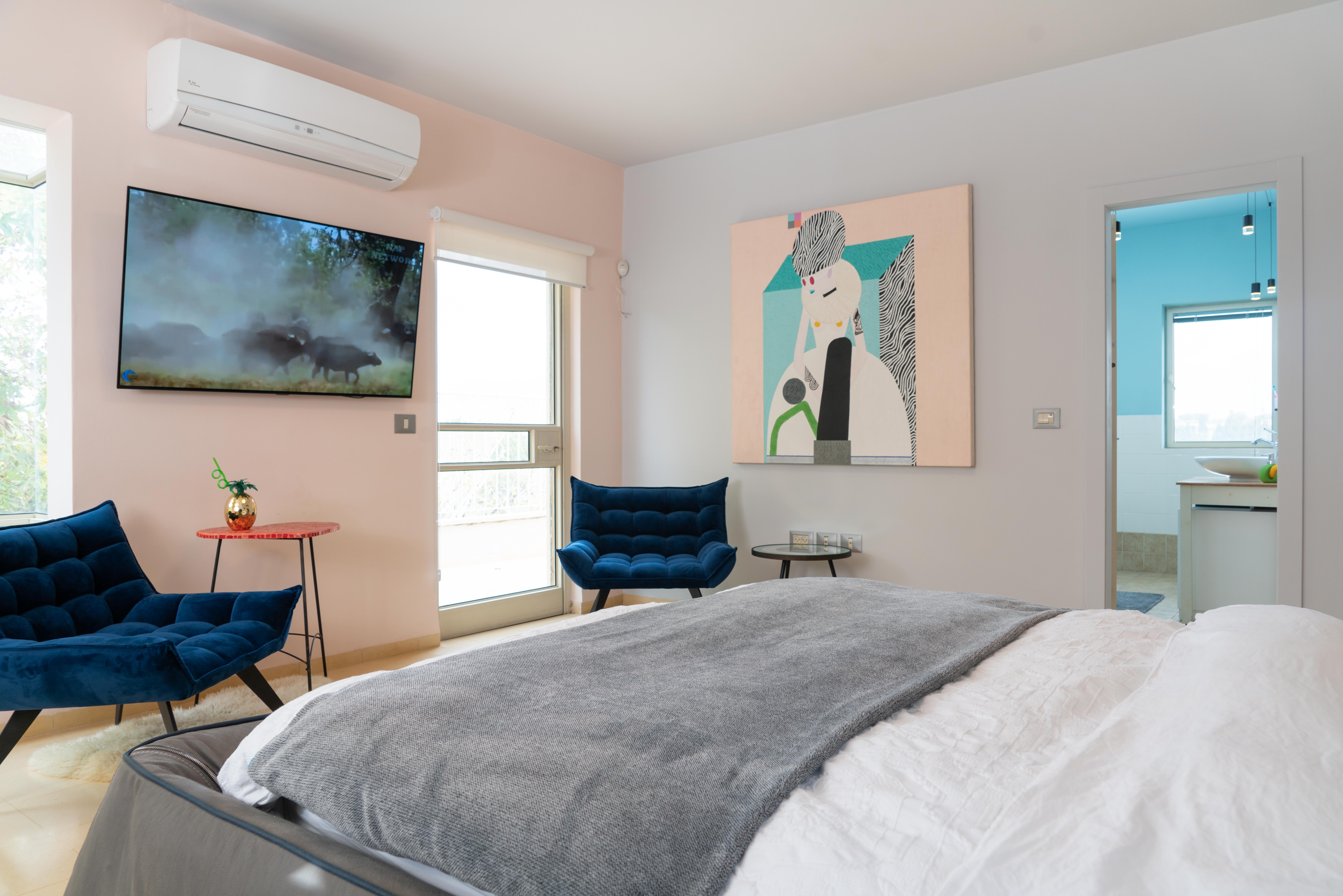 מיטה מסודרת עם טלוויזיה ותמונה על הקיר בחדר שינה