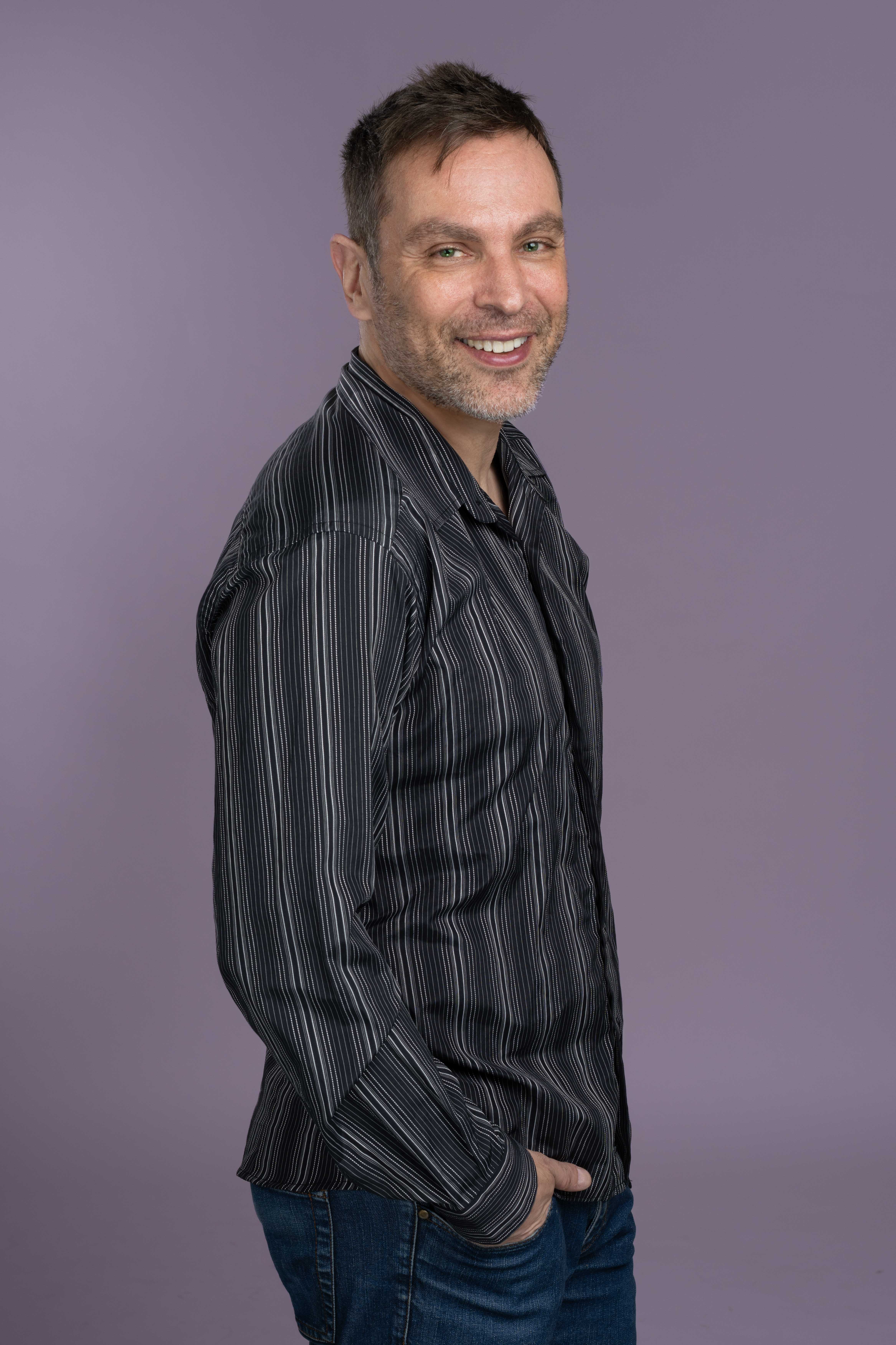 גבר עם חולצת פסים בזווית מחייך למצלמה